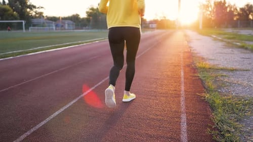 Woman Running on Track During Sunrise