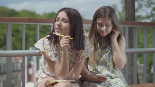 Two Young Women Sitting Outside Writing