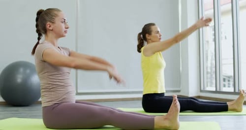 Two Women Practicing Yoga Stretches Indoors