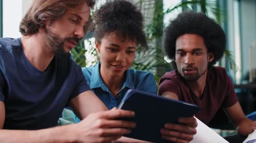 Three Coworkers Collaborating on a Tablet in Office