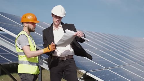 The Businessman and Worker Are Discussing Documents Standing Near Solar Batteries Outside