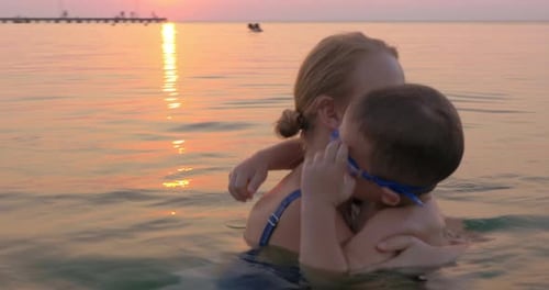 Mother and Son Swim in Ocean at Sunset