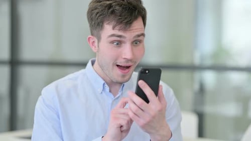 Excited Young Man Using Smartphone