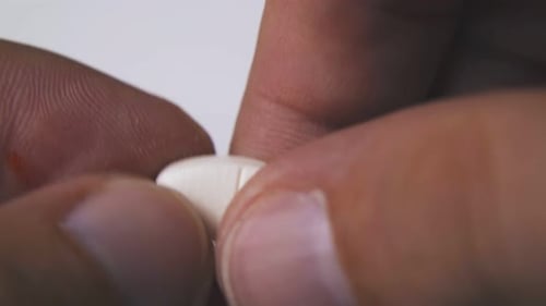 Hands Breaking Pill in Half Close Up