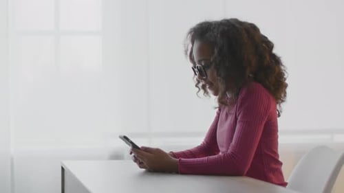 Woman Using Smartphone at Desk Indoors