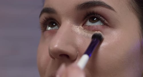 Woman Applies Concealer with Makeup Brush, Close Up