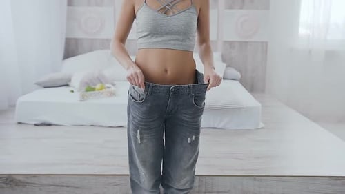 Woman Showing Weight Loss in Over-sized Jeans