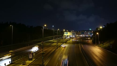 Cars Move Along Lit Highway at Night