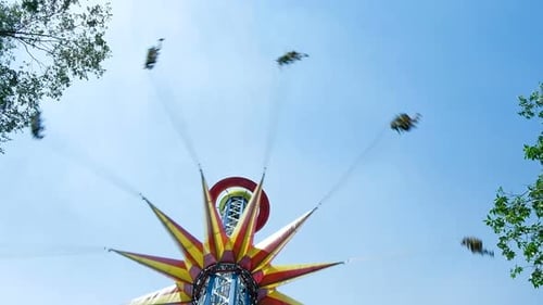 Colourful Sky Flyer Rotates People Under Clear Blue Sky