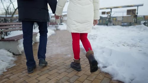 Couple Holding Hands Walking in Snowy Urban Park