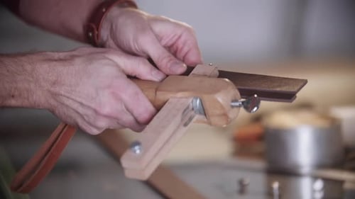 Man Cutting Leather Strip with Hand Tool