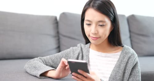 Woman Using Smartphone on Sofa Indoors