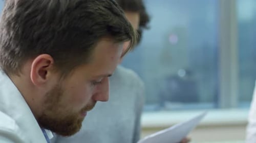 Man Working with Documents on Cardboard Boxes at Meeting with Colleagues