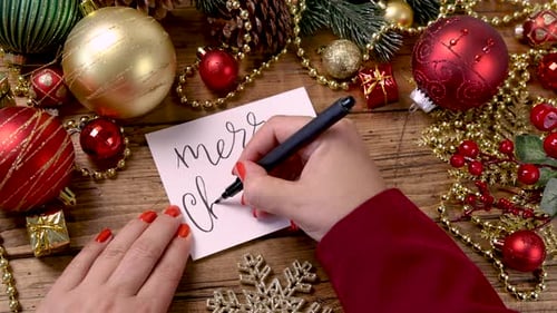 Writing Merry Christmas Greeting Card with Ornaments