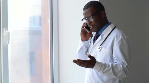 Young Male Doctor is Talking on Phone During Working Day in Modern Clinic Spbas