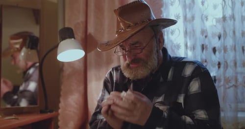 Senior Man Wears Cowboy Hat and Wipes Sweat