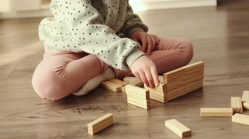 El
niño pequeño juega un juego de mesa, el niño construye con bloques de ladrillos de madera.