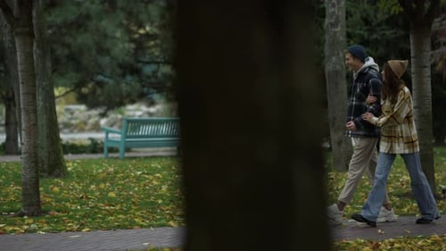Lächelnde junge Liebhaber gehen im schönen Herbstpark spazieren