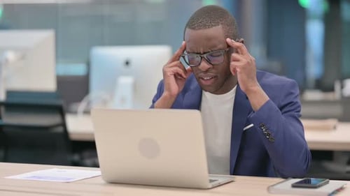Stressed Businessman Working at Desk With Laptop