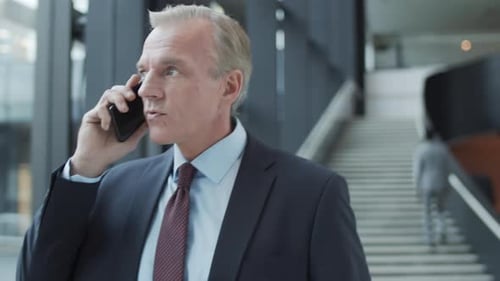 Middle-Aged Caucasian Businessman Talking on Mobile in Office Lobby
