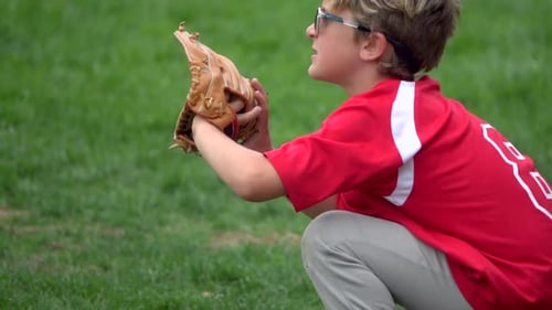 A boy practices playing catch on a little league baseball field.