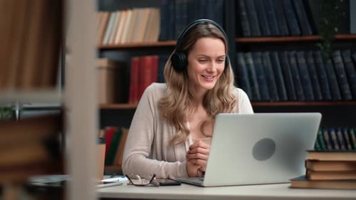 Smiling Woman in Headphones Talking Online Video Call Laptop Videochat Consulting Working at Library