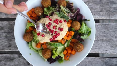 Fork Twisting Hummus on Salad in Bowl