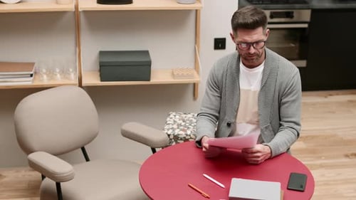 Man Reviews Documents then Answers Smart Phone