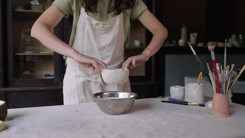 Woman Immersing Ceramic Cup in Stainless Steel Bowl