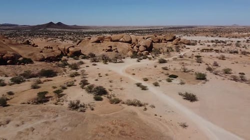 Vista de un Zumbido en un desierto con rocas enormes y muchas plantas del desierto, Namibia