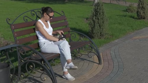 Woman Applies Hand Sanitizer on Park Bench