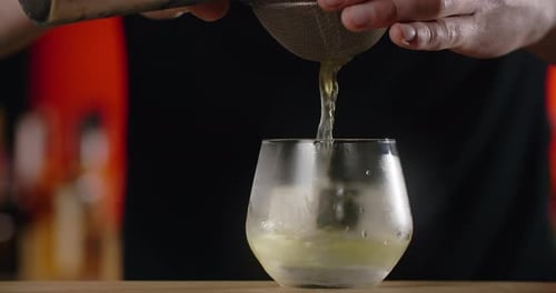 Bartender Pouring Cocktail into Glass with Ice