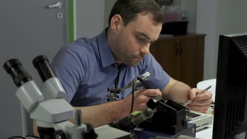 Close-up Portrait of Electronics Maintenance Engineer Soldering Motherboard, Microchip