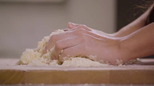 Hands Mixing Flour for Dough on Board