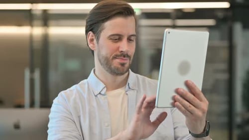 Man Celebrates Positive News on Tablet in Office