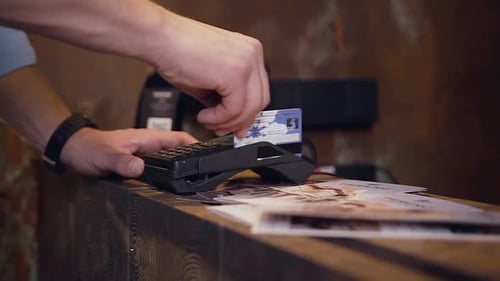 Male Hand Holding Plastic Credit Card Making Payment for Residence in Hotel
