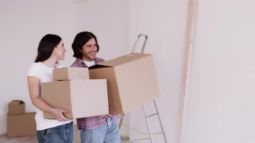 Smiling Couple Moving Boxes into New Home