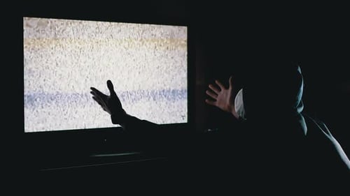 Silhouette Man in Hood and Medical Mask Watching TV Interference with Hands Up