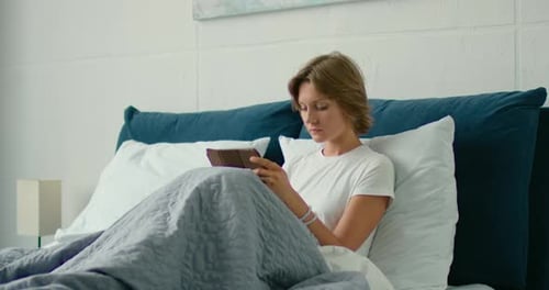 Woman Relaxing in Bed Using Tablet Device