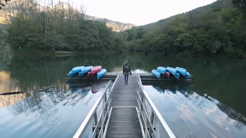 Distant traveler standing on pier enjoying scenery of peaceful lake