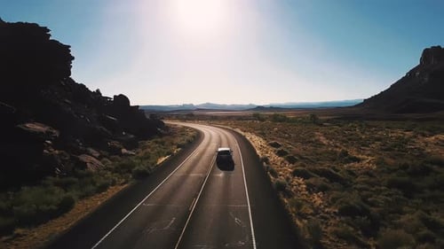 Drohnen-Kamera folgt Minivan-Auto, das auf der Desert Highway Road zwischen atemberaubendem