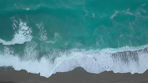 Aerial Top Down Turquoise Sea Waves Foaming and Splashing Reaching Shore From Above Empty Beach