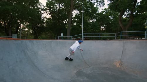 Roller Skater agressif faisant des tours dans un skatepark en béton à l'extérieur pendant le coucher du soleil