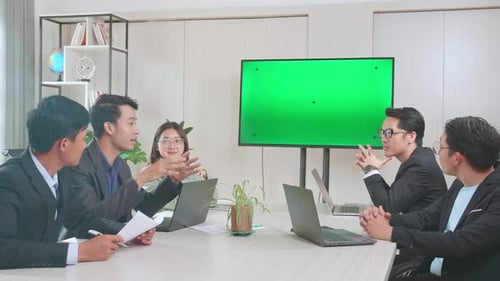 Young Asian Team Have Meeting In A Conference Room. They Share Opinions With Tv Mock Up Green Screen