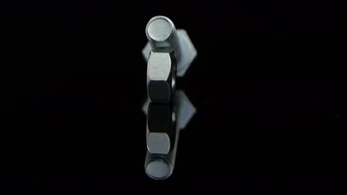 Nut and Bolt Rotate on Glass Black Stand in Closeup