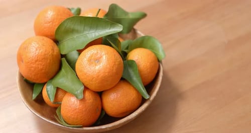Vibrant Tangerines in a Wooden Bowl on Table