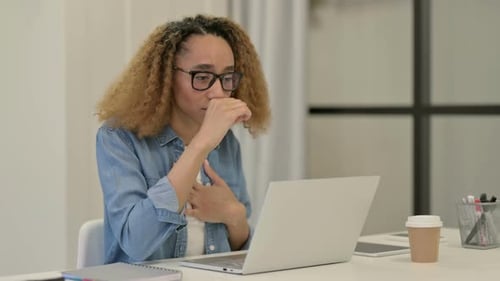 Woman Coughing While Working on Laptop at Home