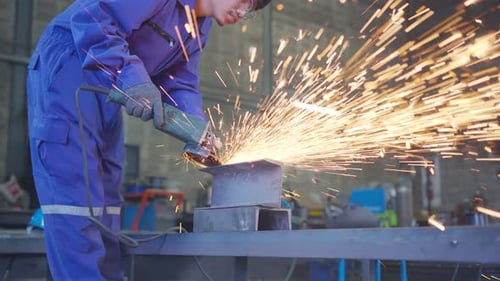 Worker Grinding Metal with Sparks in Workshop
