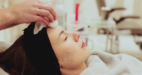 Beautician Cleaning Woman's Face in Beauty Clinic