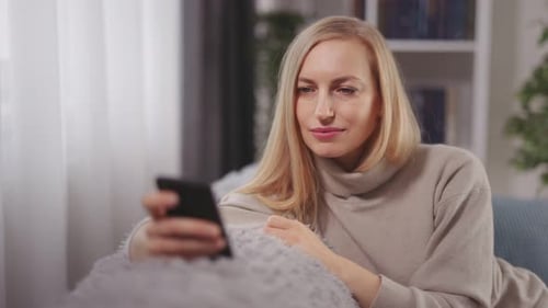 Woman Relaxing on Couch Using Smartphone